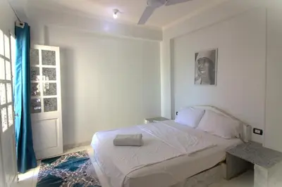 a bedroom with a white bed and a window at Mama Africa Apts & Studios in Luxor