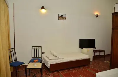 a room with a bed and two chairs and a tv at Dolphin Hotel Safaga in Safaga