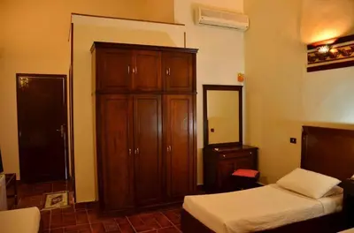a bedroom with a bed and a wooden cabinet at Dolphin Hotel Safaga in Safaga