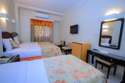 a hotel room with two beds and a mirror at Cleopatra Hotel in Aswan