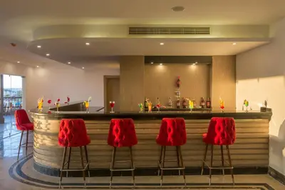 a bar with red chairs in front of a counter at Gravity Hotel & Aqua Park Sahl Hasheesh Families and Couples Only in Hurghada