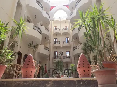 a large building with palm trees and plants in it at Al Hambra Hotel in Luxor