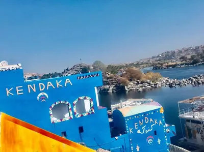 a blue building next to a body of water at Kendaka Nubian House in Aswan