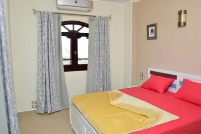 a bedroom with a bed with red and yellow sheets and a window at The View El Quseir in Quseir