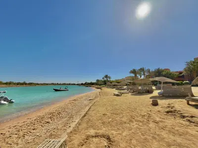 a beach with chairs and a boat in the water at Lagoon view 1-bedroom apartment in West Golf El Gouna in Hurghada