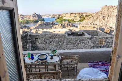 a table and chairs on a balcony with a view of a river at Eco Nubia in Aswan