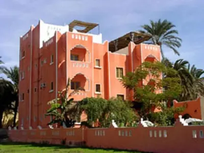a red building with a fence in front of it at El Fayrouz Hotel in Luxor