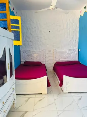 two beds in a room with blue and white walls at Tongel Nubian Studio & Guest House in Aswan