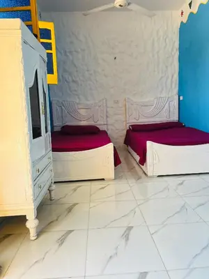 two beds in a room with blue and white walls at Tongel Nubian Studio & Guest House in Aswan