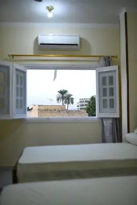 a bedroom with two beds and a window with a view of the beach at Kosh royal house in Aswan