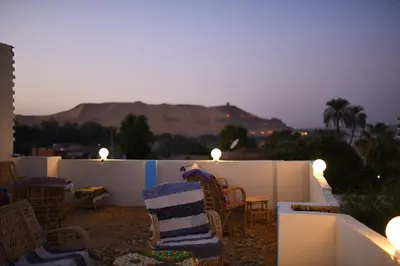 a man sitting on a balcony with a table and chairs at Kosh royal house in Aswan