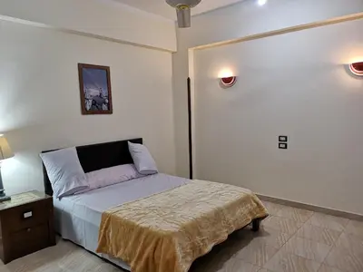 a small bedroom with a bed and a night stand at Luxor hotel Bella Vista Apartments and Hotel in Luxor