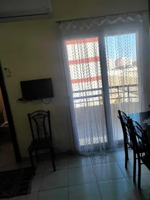 a living room with two chairs and a television and a table at Studio Apartment at Tiba Star in Hurghada