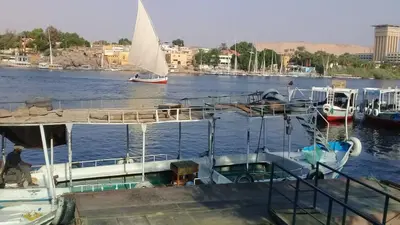 a boat is docked in a river with a sailboat at Elephantina sobek guest house in Aswan