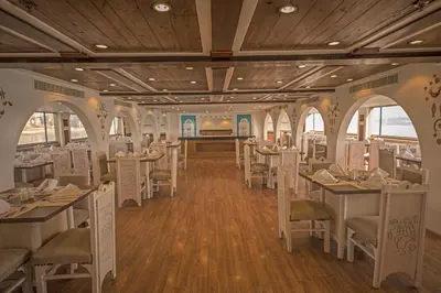 a restaurant with white tables and chairs and wooden ceilings at SUNRISE Mahrousa Cruise in Luxor