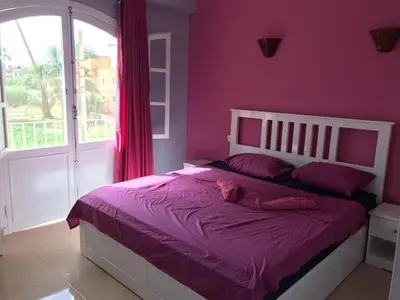 a bedroom with a bed with purple sheets and a window at Hermina Guest House in Luxor