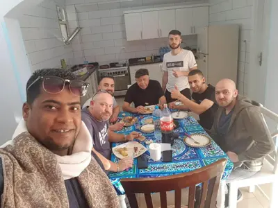a group of men sitting around a table eating food at Hermina Guest House in Luxor