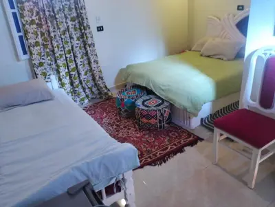 a bedroom with two beds and a chair and a rug at Roma House in Aswan