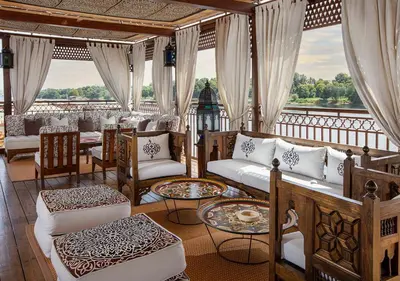 a room with couches and tables on a balcony at Dahabeya Yakouta Nile Cruise-Every Monday from Luxor- Aswan for 05 nights in Luxor