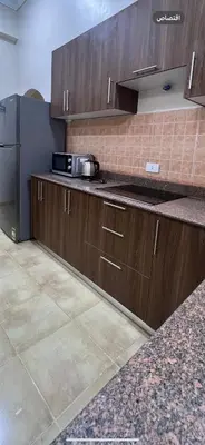 a kitchen with wooden cabinets and a black refrigerator at Karnak Flats in Luxor