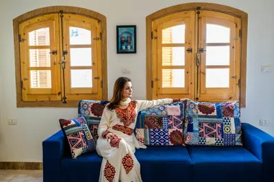 a woman sitting on a blue couch with pillows at Dar Lina Guesthouse Luxor in Luxor