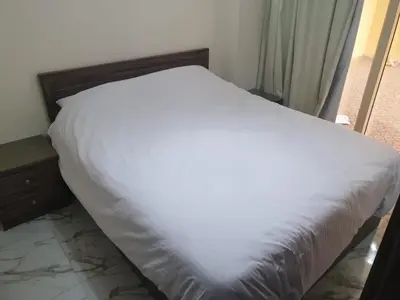 a bed with a white sheet on top of it at Bravey Apartments in Hurghada