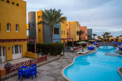 a pool at a resort with blue chairs and palm trees at Al Dora Boutique Hotel in Hurghada