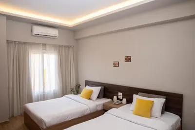 two beds in a hotel room with yellow pillows at Al Dora Resort Hurghada in Hurghada