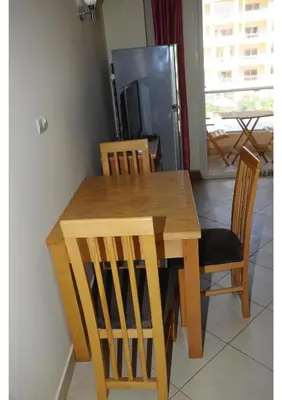 a wooden dining room table with chairs and a refrigerator at Apartment I in Florenza Khamsin in Hurghada