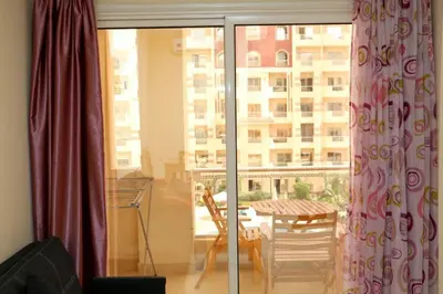 a room with a balcony with a table and a window at Apartment F in Florenza Khamsin in Hurghada