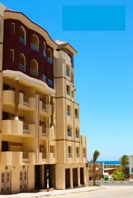 a building next to the beach with the ocean in the background at Apartment G in Florenza Khamsin in Hurghada