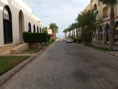an empty street with palm trees and buildings at Beachfront Cozy One Bedroom apartment Sahl Hasheesh Palma de Piazza in Hurghada