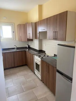 a kitchen with wooden cabinets and a white refrigerator at Bahga Palace 4 Residential Apartments in Hurghada