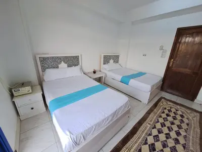 a bedroom with two beds and a door in it at NOBATiA Guest House in Aswan