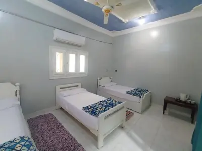 a white room with two beds and a ceiling at Winji Guest house in Aswan