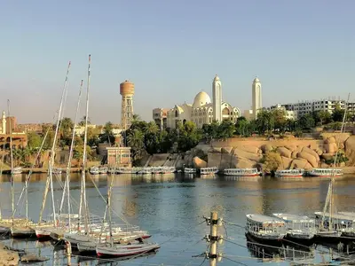 a group of boats docked in a river with a city at Winji Guest house in Aswan