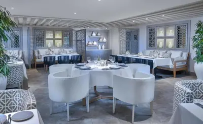 a dining room with white tables and white chairs at Steigenberger Resort Ras Soma in Hurghada
