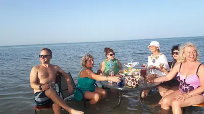 a group of people sitting around a table in the water at Coral Paradise Villa in Safaga