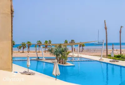 a swimming pool with umbrellas and the beach at Ollystays Mangroovy Seaview 1BR Beach and Pool Free access in Hurghada