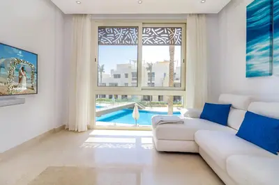a living room with a white couch and a window at Ollystays Mangroovy Seaview 1BR Beach and Pool Free access in Hurghada