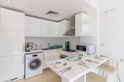 a kitchen with white cabinets and a washer and dryer at Ollystays Mangroovy Seaview 1BR Beach and Pool Free access in Hurghada