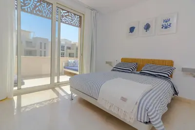 a white bedroom with a bed and a large window at Ollystays Mangroovy Seaview 1BR Beach and Pool Free access in Hurghada