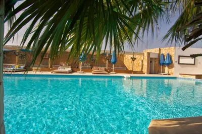 a large blue swimming pool with chairs and umbrellas at AJIRA Boutique Hotel Hurghada Marina in Hurghada