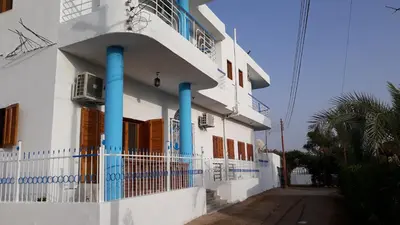 a white building with blue columns and a balcony at Hofni Palace Nile Niew in Luxor