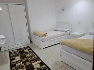 a white room with two beds and a rug at Hofni Palace Nile Niew in Luxor