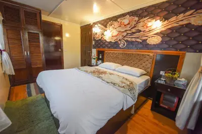 a bedroom with a large bed and a painting on the wall at Dahabiya ECO Queen Cleopatra in Esna