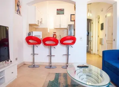 a living room with red stools and a glass table at El Gouna 1 bedroom apartment in West Golf Y12 in Hurghada