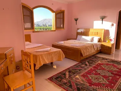 a bedroom with two beds and a window and a rug at Elsanosy Family Guest House - Luxor in Luxor