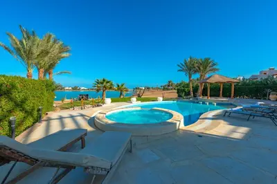 a swimming pool with chaise lounge chairs and a swimming poolvisor at 4 Bedroom Villa with Heated Pool, Jacuzzi & Lagoon View in Phase 4 in Hurghada