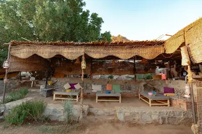 an outdoor patio with chairs and tables and a roof at Krouma Camp & Ecolodge in Aswan